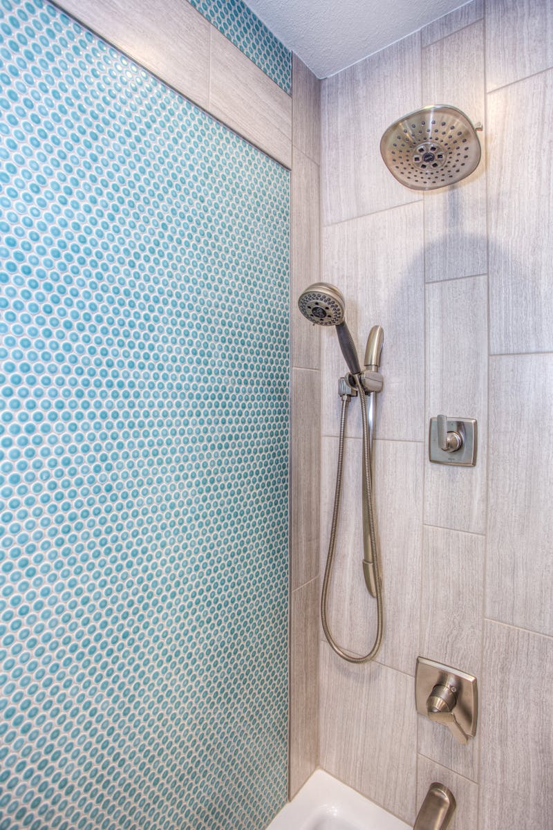 why-choose-us Elegant shower design featuring blue mosaic tiles and stainless steel fixtures.